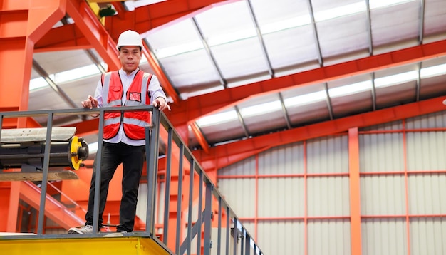 Operaio ingegnere di fabbrica che opera una macchina per tetto in lamiera presso la produzione di industria pesante Operaio in elmetto protettivo di sicurezza presso le strutture industriali della fabbrica