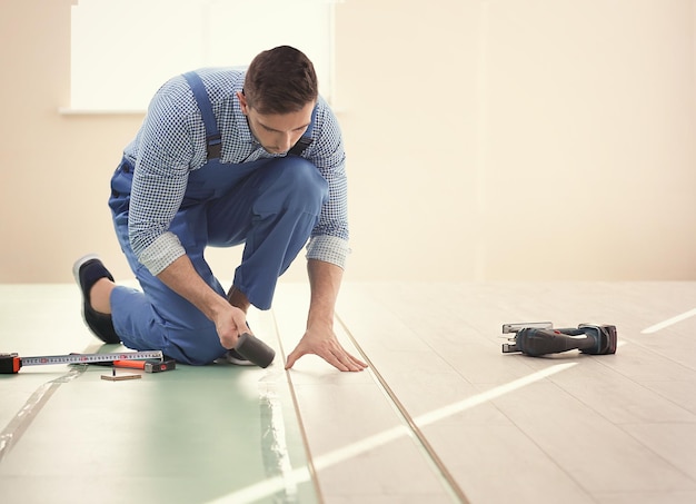 Operaio maschio che installa pavimenti in laminato