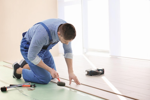 Operaio maschio che installa pavimenti in laminato