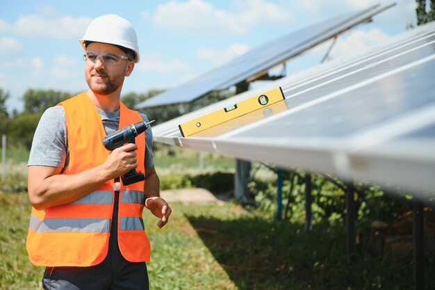 Operaio maschio con batterie solari. Uomo in un casco protettivo. Installazione di un sistema di pannelli solari autonomo