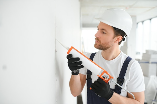 Operaio professionista che applica sigillante siliconico con pistola per silicone sulla parete