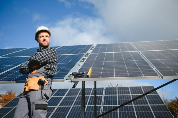 Operaio professionista che installa pannelli solari sulla struttura in metallo utilizzando diverse apparecchiature che indossano il casco Soluzione innovativa per la risoluzione energetica Utilizzare risorse rinnovabili Energia verde