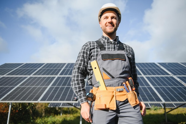 Operaio professionista che installa pannelli solari sulla struttura in metallo utilizzando diverse apparecchiature che indossano il casco Soluzione innovativa per la risoluzione energetica Utilizzare risorse rinnovabili Energia verde