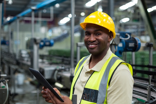 Operaio sorridente che utilizza compressa digitale nella fabbrica