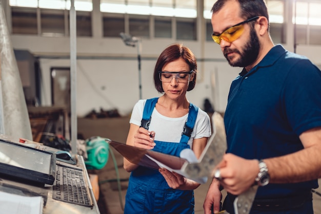 Operatore CNC e ingegnere industriale che controllano il disegno del prodotto