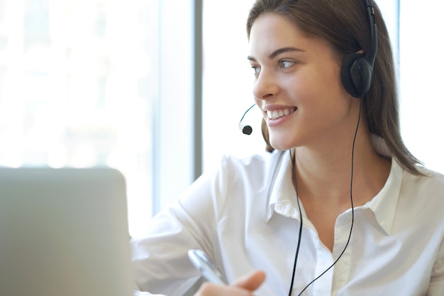 Operatore di assistenza clienti femminile con auricolare e sorridente.