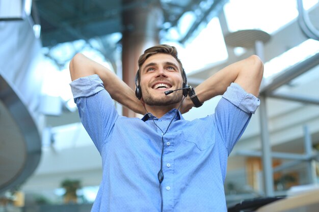 Operatore di call center in cuffia che riposa sul posto di lavoro in ufficio.