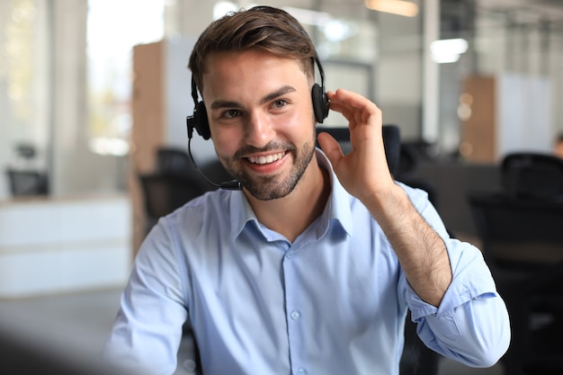 Operatore di call center maschio giovane bello sorridente amichevole.