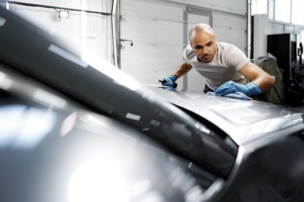 Operatore di servizio di auto uomo afroamericano che applica nano rivestimento su un'auto