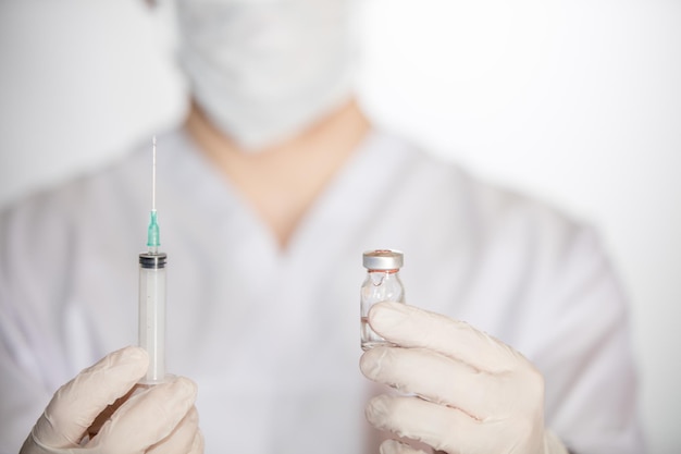 Operatore sanitario che tiene siringa e flaconcino con vaccino contro COVID-19, morbillo e influenza