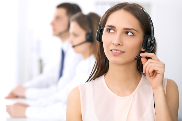 Operatori di call center. Focus su giovane bella donna d'affari in cuffia.