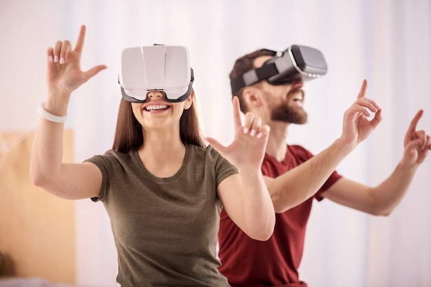 Opportunità di realtà virtuale. Gioiosa donna allegra positiva muovendo le mani mentre sorride e indossa l'auricolare Vr