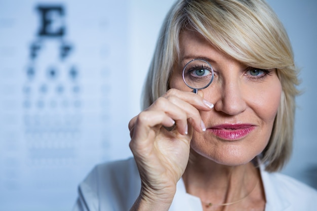 Optometrista femmina guardando attraverso la lente di ingrandimento