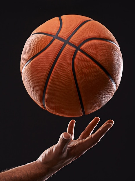 È ora di aumentare il tuo gioco Immagine ritagliata di una mano di un uomo che tiene un pallone da basket su uno sfondo nero