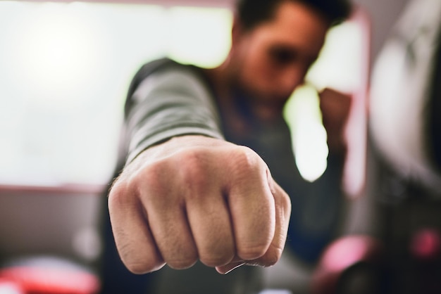 È ora di mettere al lavoro questi ragazzi Primo piano di un giovane pugile concentrato che lancia pugni alla telecamera all'interno di un anello in una palestra durante il giorno