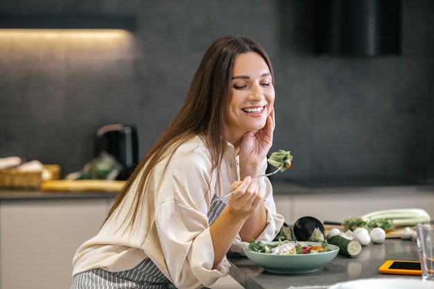 Ora di pranzo. Donna felice sorridente che mangia con appetito