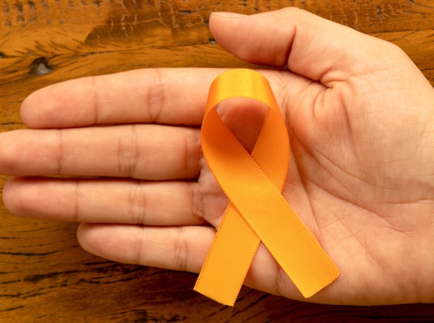Orange August Campagna di sensibilizzazione sulla sclerosi multipla Mano che tiene il nastro arancione