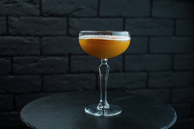 Orange delizioso cocktail dolce con tonico e vodka con sciroppo dolce nel ristorante sulla tavola di legno su sfondo nero. Cocktail alcolici originali. Fine settimana al bar