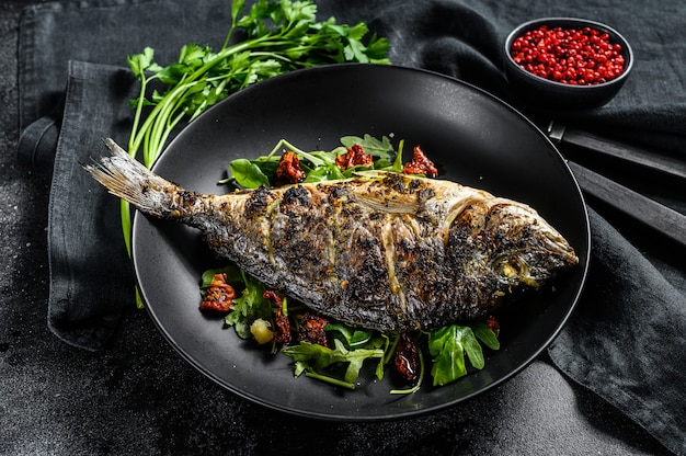 Orata al forno con insalata di rucola e pomodori. vista dall'alto