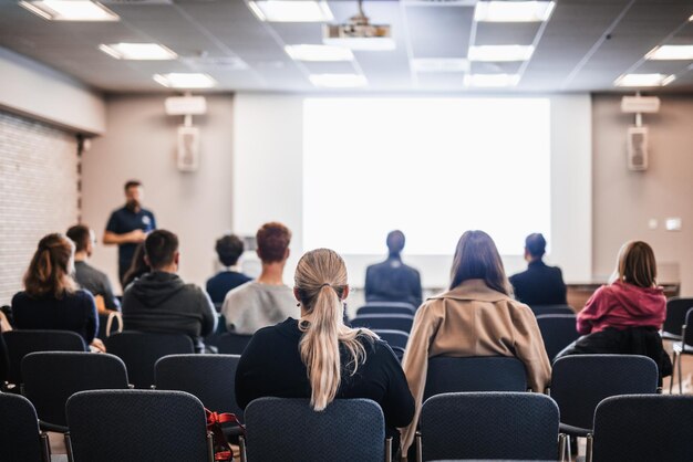 Oratore che tiene un discorso in una sala conferenze in un evento aziendale vista posteriore di persone irriconoscibili in