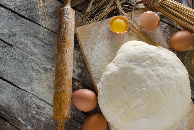 Orecchie di pasta impastate di uova di mattarello e una bottiglia di olio sul vecchio primo piano rustico della tavola