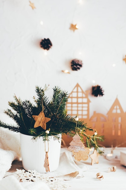 Organizzazione di una tavola natalizia festiva. Mazzo di abete in un vaso decorato con ornamenti in legno sulla tavola di Natale. Stile di vita ecologico e casalingo. Vista verticale