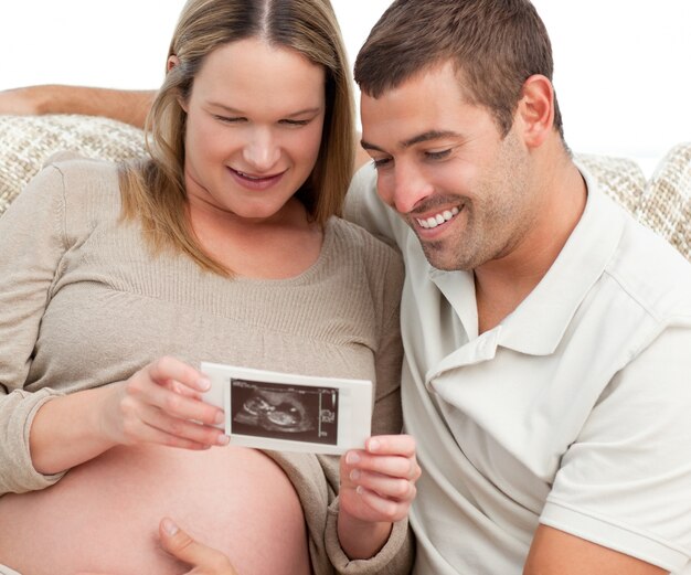 Orgoglioso futuro papà guardando un&#39;ecografia con sua moglie