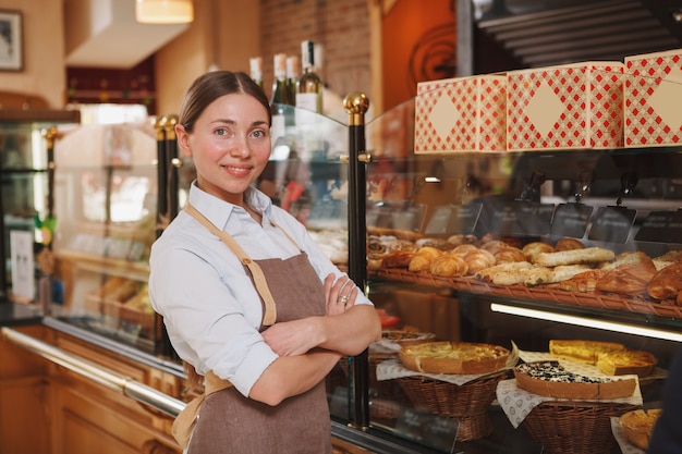 Orgoglioso panettiere che sorride alla telecamera, lavorando nel suo negozio di panetteria, copia dello spazio