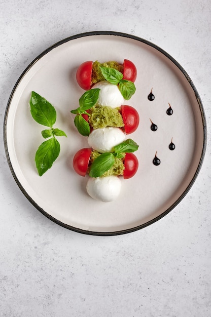 Orientamento verticale deliziosa insalata caprese italiana con pomodori maturi, basilico fresco giardino e mozzarella
