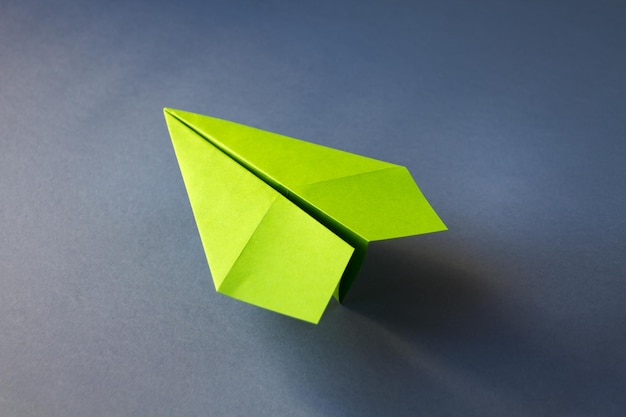 Origami aereo di carta verde isolato su sfondo grigio