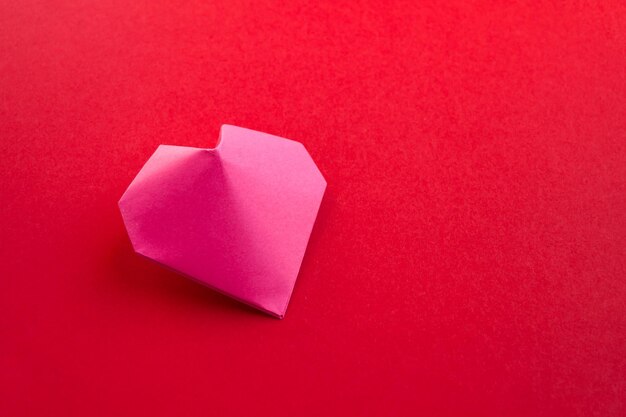 Origami cuore di carta rosa isolato su sfondo rosso