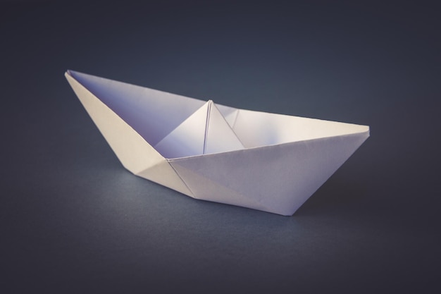 Origami di barca di carta bianca isolati su sfondo grigio