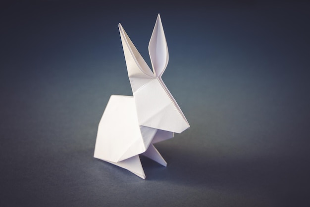 Origami di coniglio di carta bianca isolato su sfondo grigio