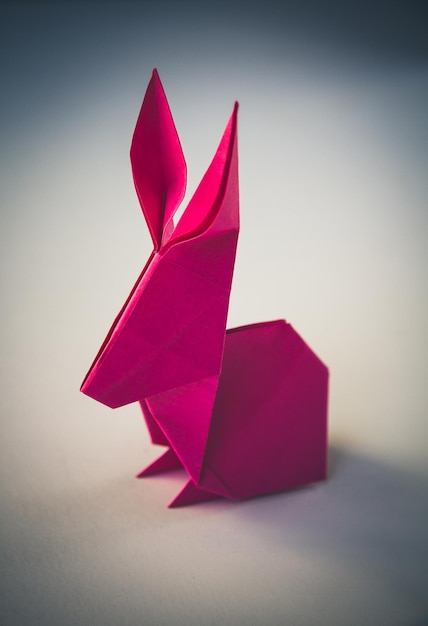 Origami di coniglio di carta rosa isolato su sfondo bianco