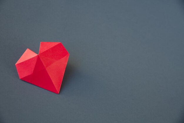 Origami di cuore di carta rossa isolato su sfondo grigio