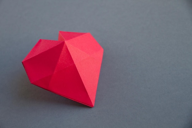 Origami di cuore di carta rossa isolato su sfondo grigio