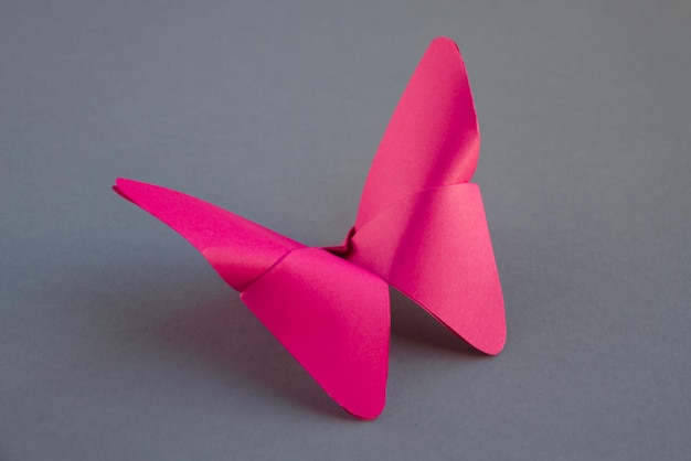 Origami di farfalla di carta rosa isolato su sfondo grigio