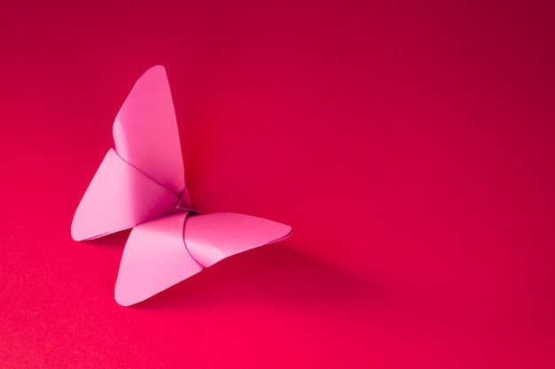 Origami di farfalla di carta rosa isolato su sfondo rosso