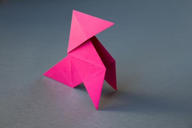 Origami di gallina di carta rosa isolato su sfondo grigio