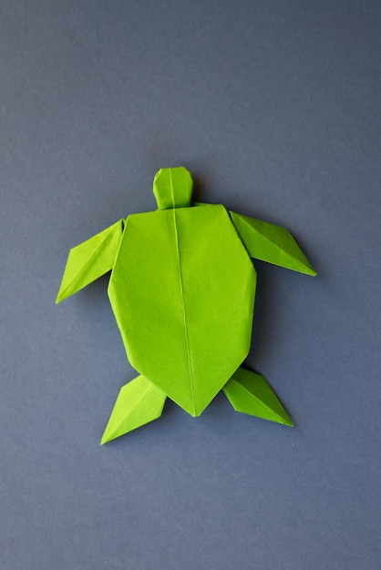 Origami di tartaruga di carta verde isolato su sfondo grigio