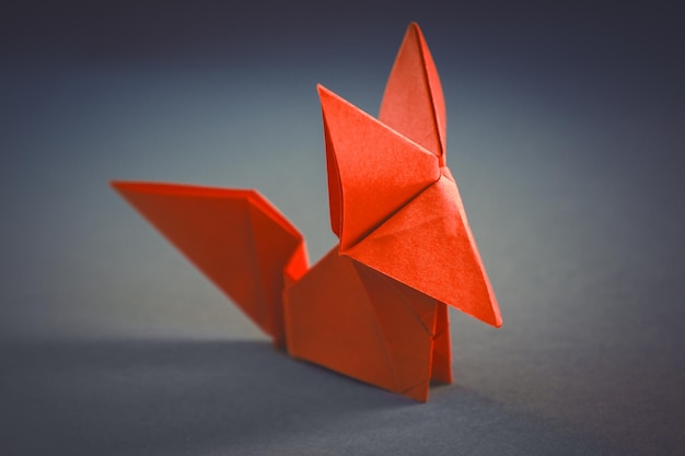Origami di volpe di carta arancione isolati su sfondo grigio