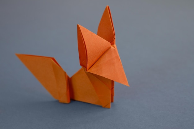 Origami di volpe di carta arancione isolati su sfondo grigio