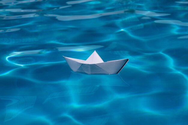 Origami nave barca di carta sullo sfondo del mare barca di carta origami che naviga sull'acqua provocando onde e