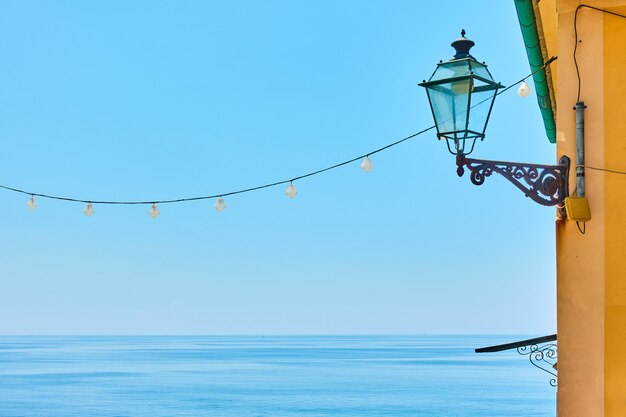 Orizzonte del mare, cielo blu chiaro e lampione vintage sul muro - sfondo con spazio per il testo, Italia