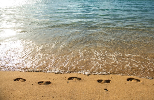 Orme sulla spiaggia tropicale di sabbia dorata con sabbia di mare durante le vacanze estive