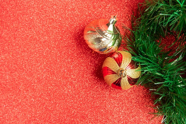 Ornamenti di Natale in plastica e glitter e ghirlanda di Natale su una superficie glitterata rossa. messa a fuoco selettiva.