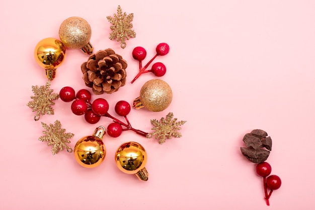 Ornamenti natalizi in oro e rosso su sfondo rosa