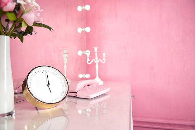 Orologi e oggetti interni sul tavolo nella stanza rosa di una giovane donna o ragazza. Copia spazio