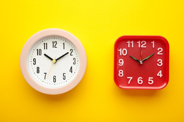 Orologio da parete rosa e rosso su sfondo giallo Foto verticale