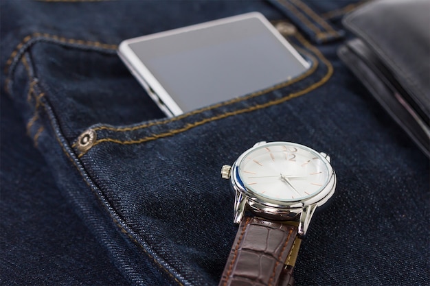 Orologio da polso e smartphone su jeans in denim